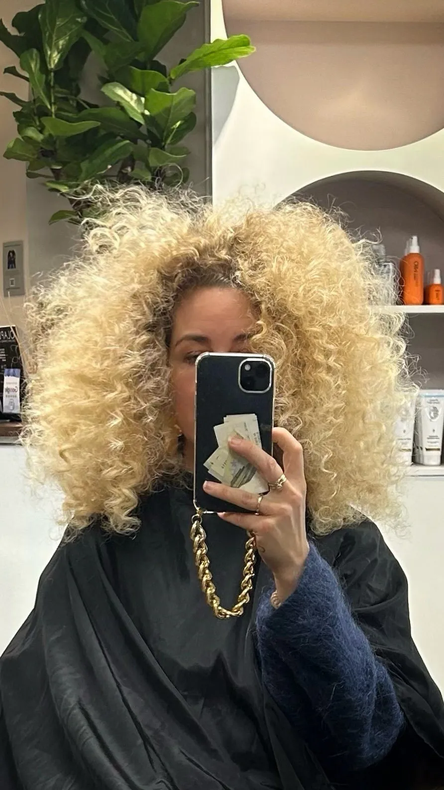 Volle blonde krullen in de kappersstoel