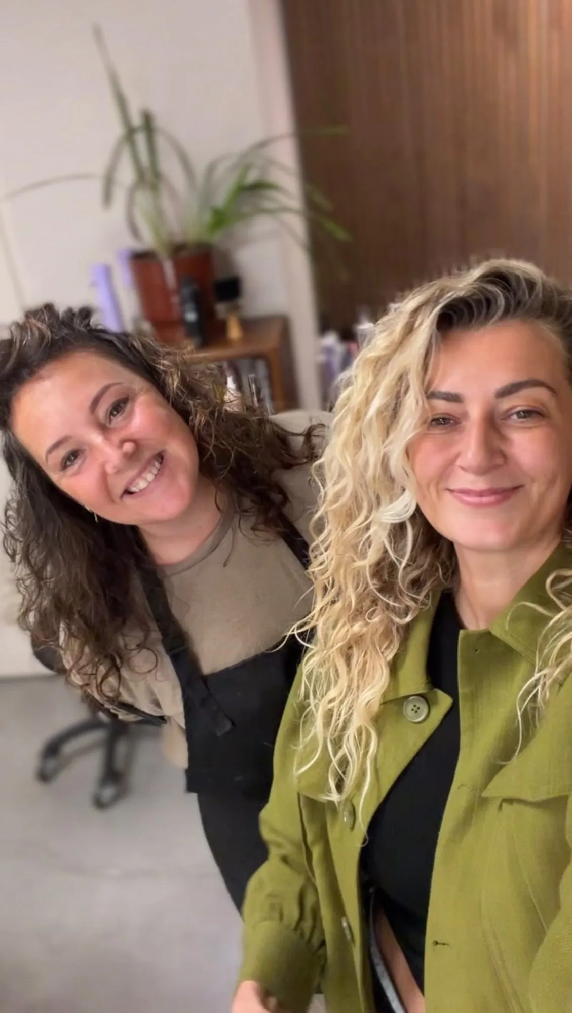 Twee collega’s met krullen lachen in de salon